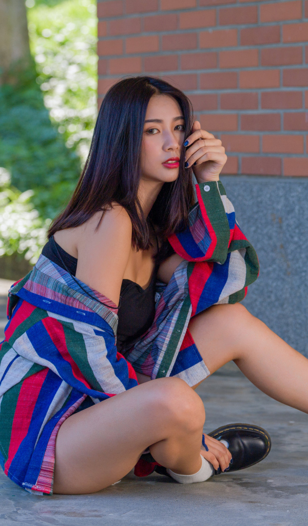 Красивая азиатка в рубашке у стены