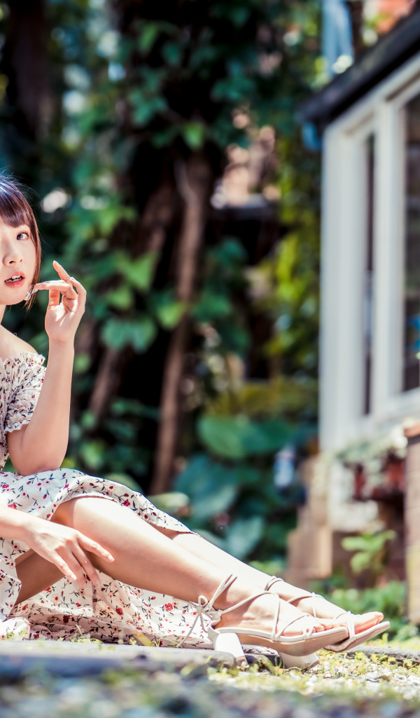 Красивая девушка азиатка в платье сидит на земле