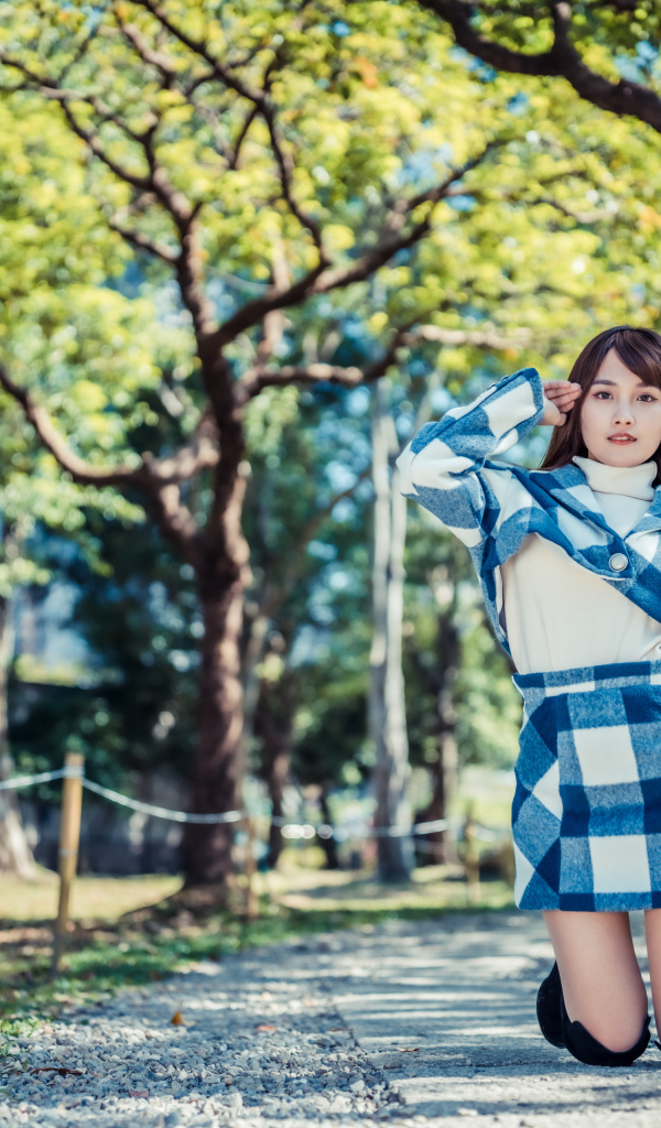 Красивая девушка азиатка стоит на коленях в парке