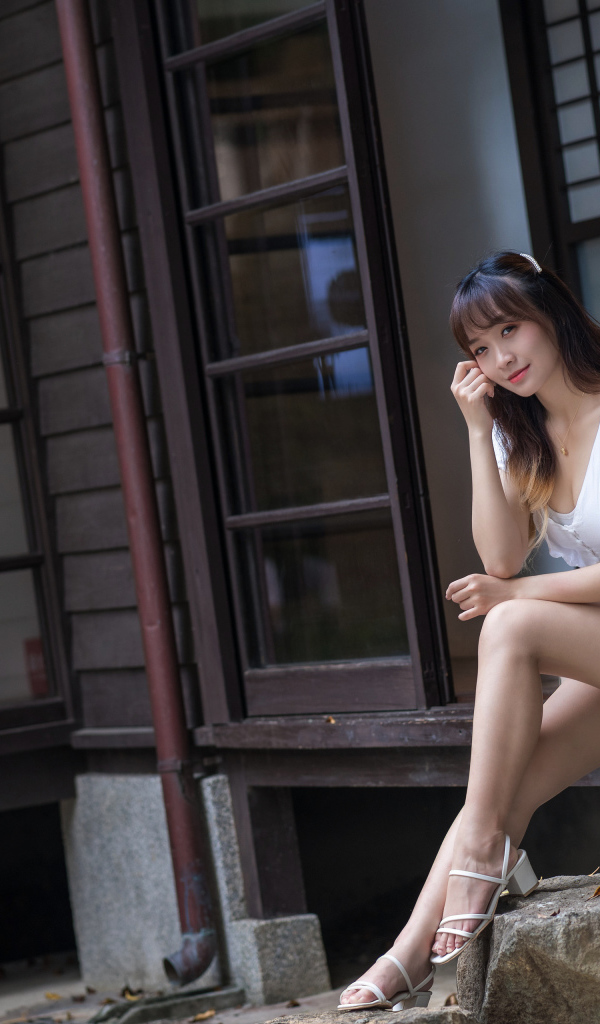 Красивая девушка азиатка сидит у двери