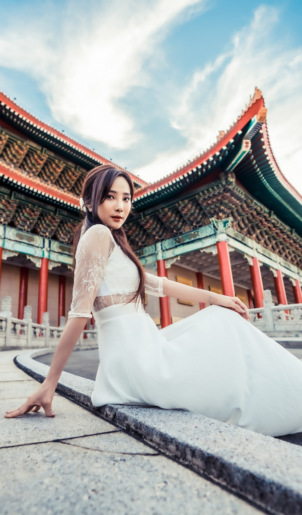 Красивая азиатка в белом платье на фоне храма