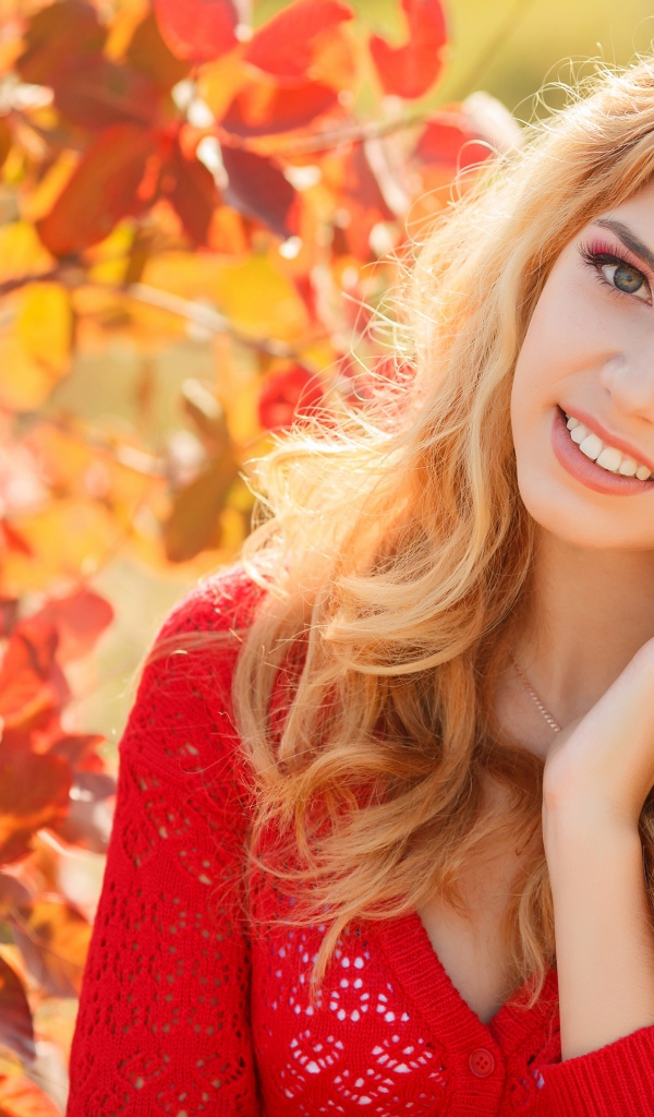 Красивая блондинка в красной кофте на улице осенью 