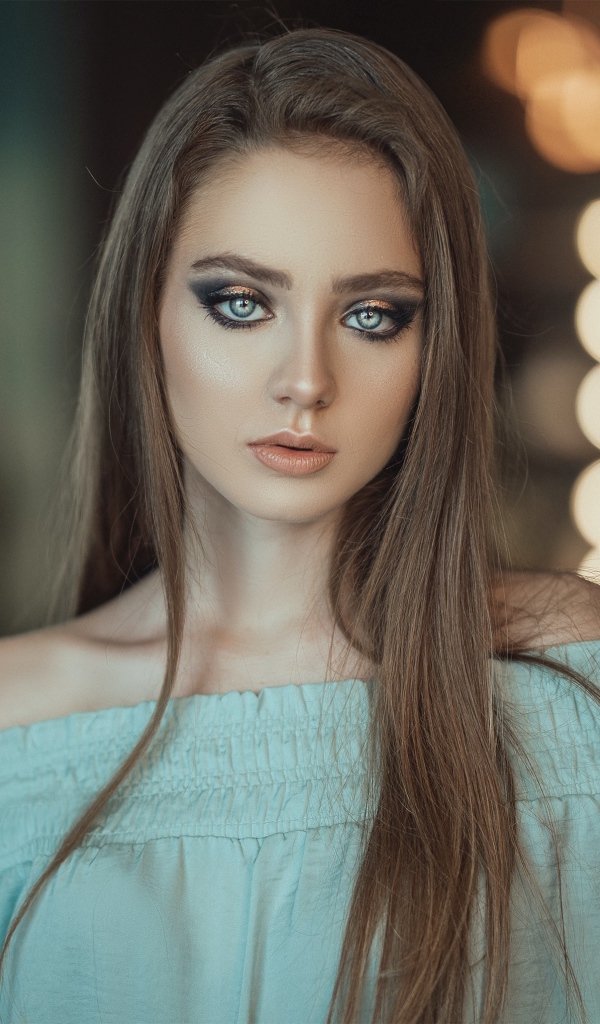 Красивая голубоглазая девушка в платье у зеркала 