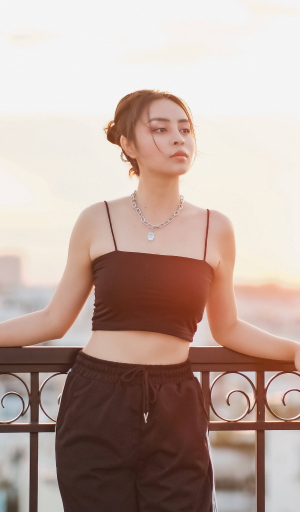 Красивая девушка в черном костюме на мосту в лучах солнца