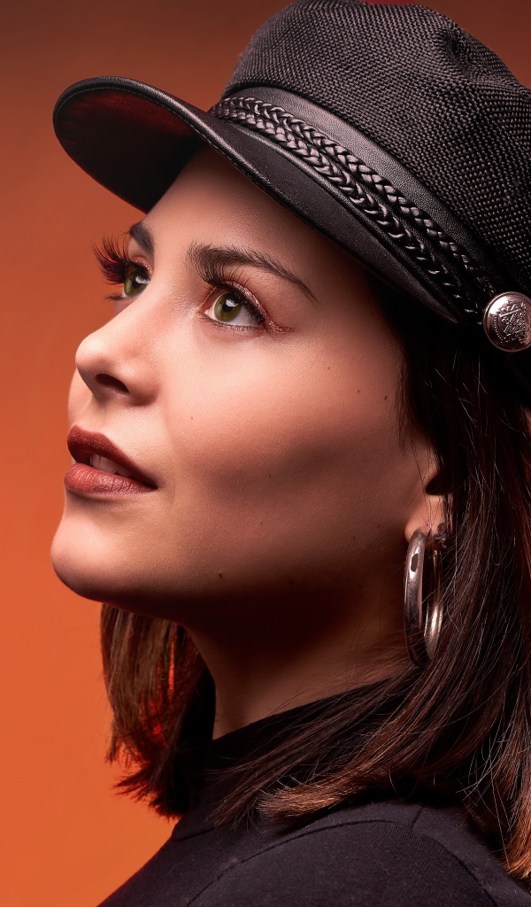 Красивая девушка в кепке на коричневом фоне