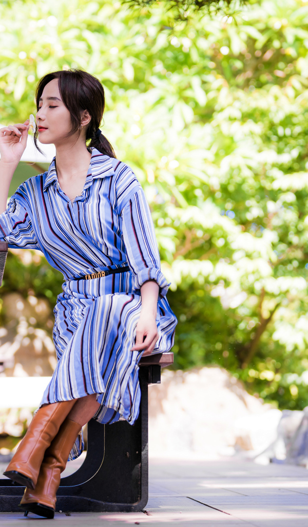 Красивая девушка в платье сидит за столиком в парке