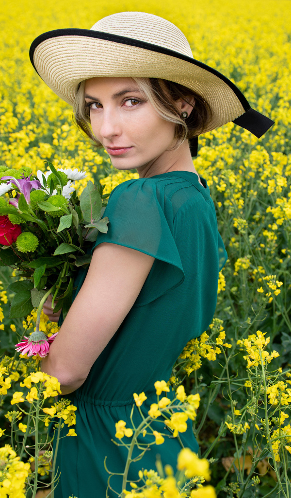 Красивая девушка в шляпе на поле с желтыми цветами летом