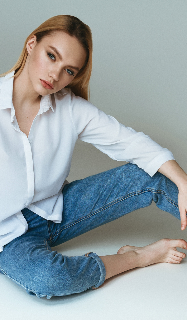 Красивая девушка в белой рубашке на сером фоне