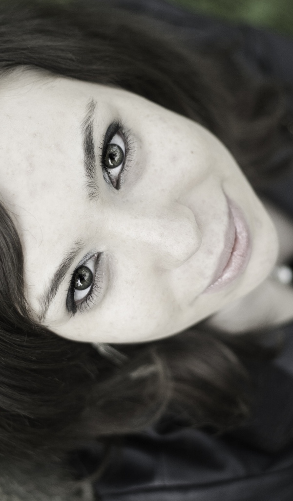 Красивая девушка смотрит вверх сидя под деревом  