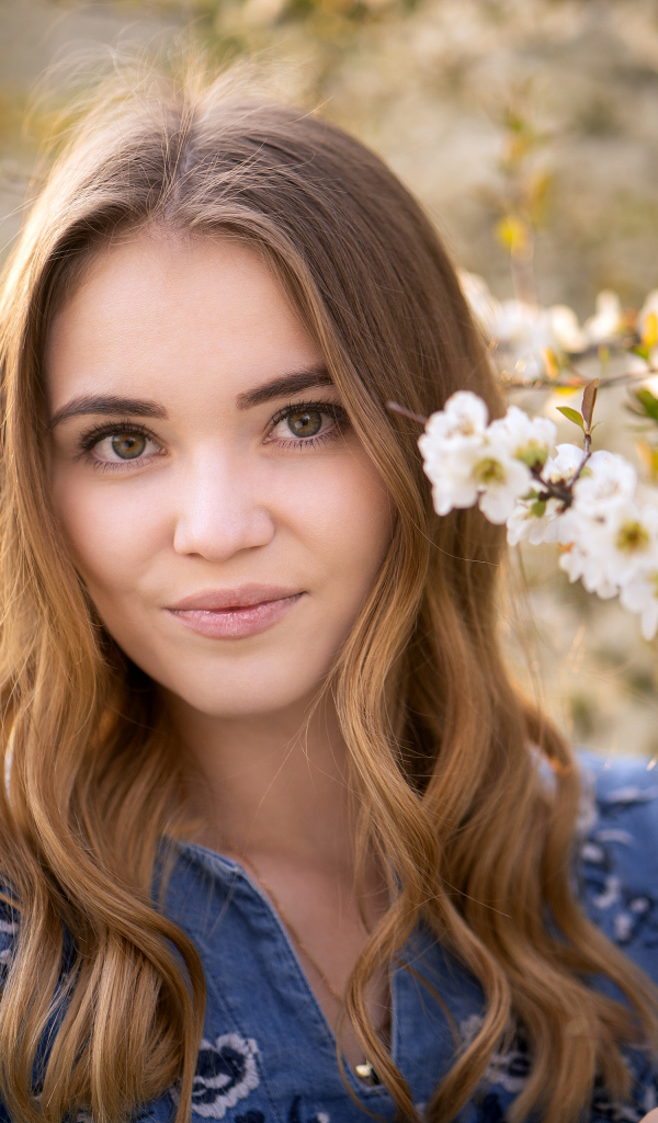 Красивая девушка у ветки с белыми цветами