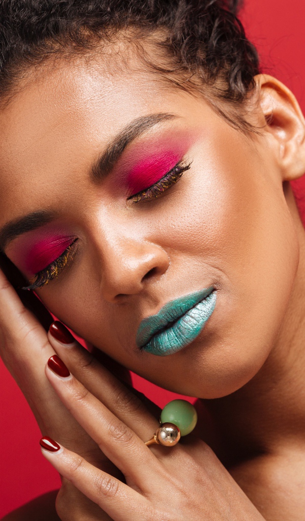 Красивая девушка с ярким макияжем на красном фоне