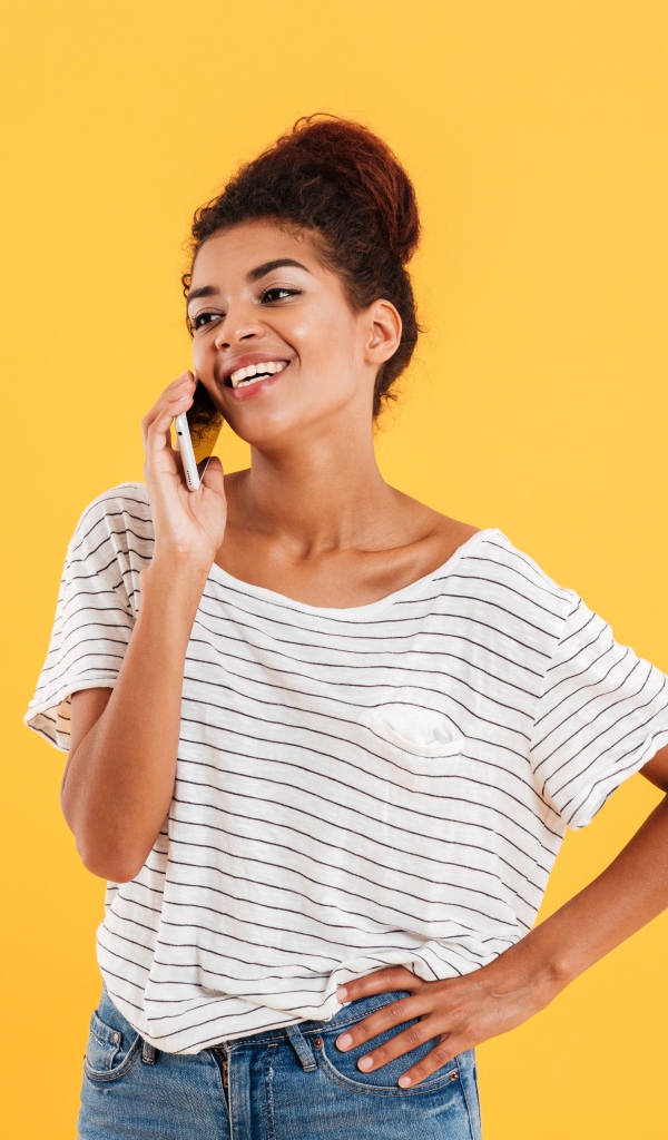 Красивая девушка со смартфоном на желтом фоне