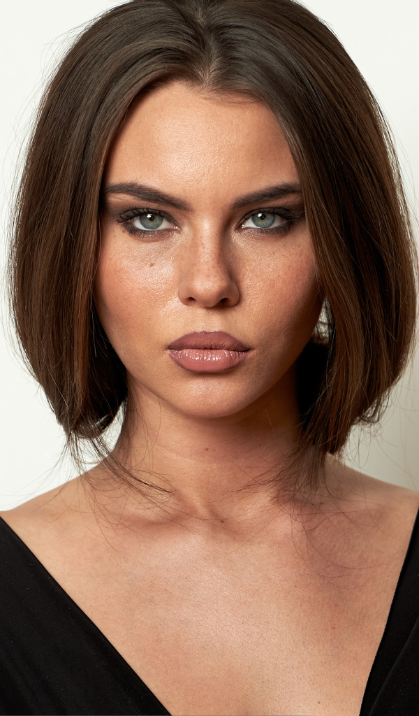 Красивая серьезная брюнетка на сером фоне