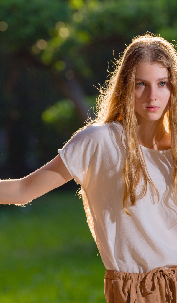 Красивая нежная девушка стоит у стены 