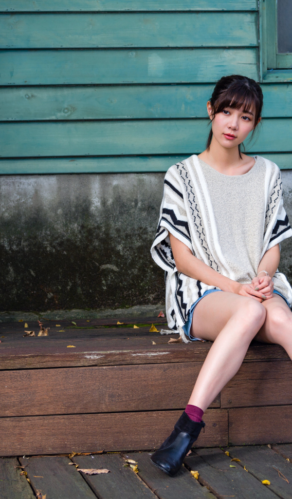 Красивая молодая девушка азиатка сидит у дома