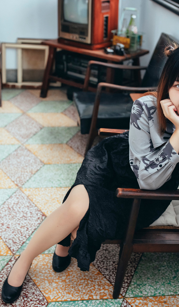 Красивая молодая азиатка сидит в кресле