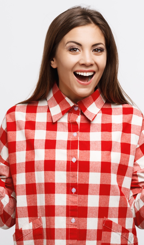 Cheerful girl in a plaid shirt on a white background