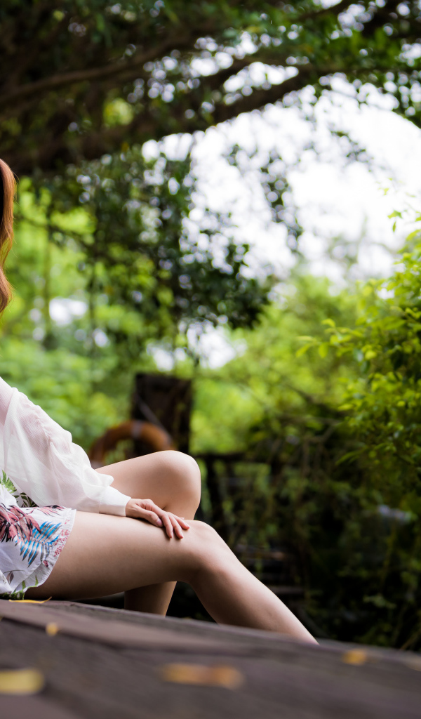 Милая девушка азиатка сидит на мосту