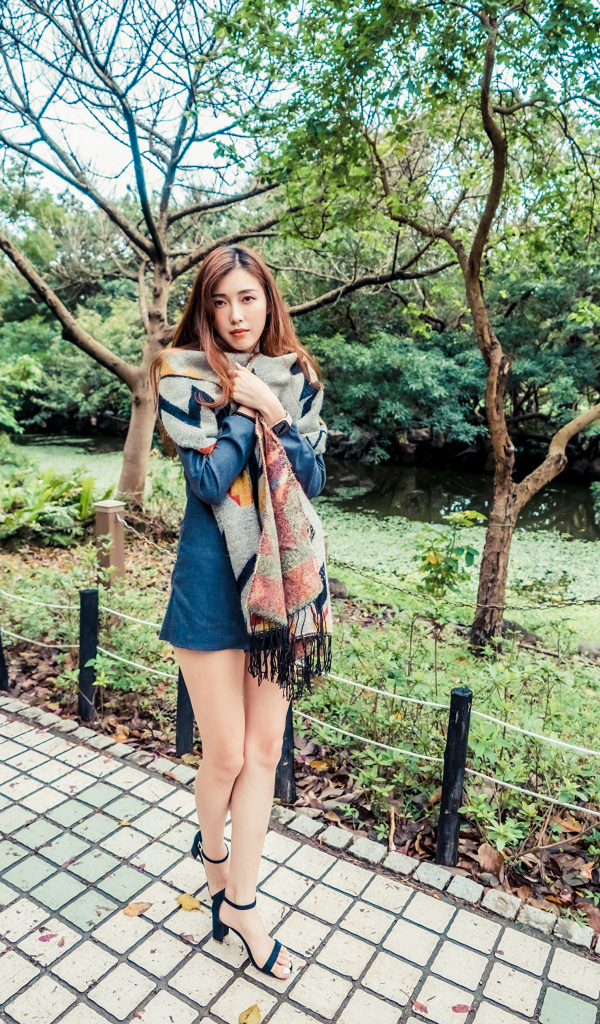 Милая девушка азиатка стоит в осеннем парке 