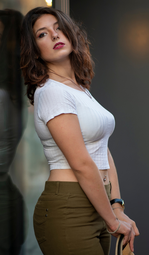 Милая девушка стоит у стеклянной двери 