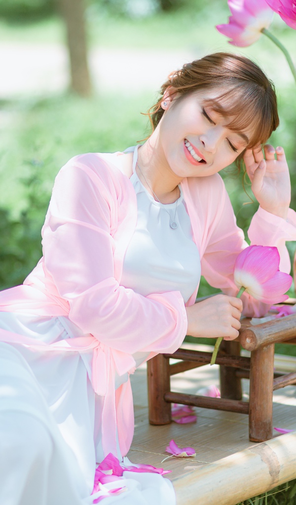 Мечтательная девушка азиатка с цветами лотоса