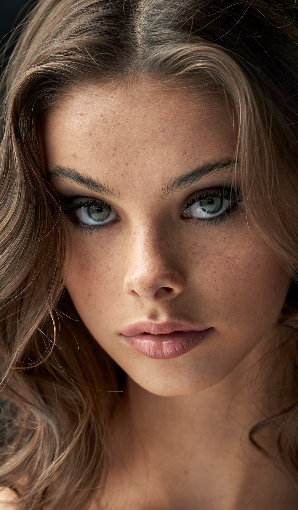 Лицо красивой девушки с веснушками на лице 