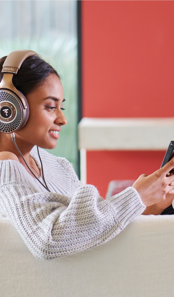 Девушка модель в наушниках на диване с плеером