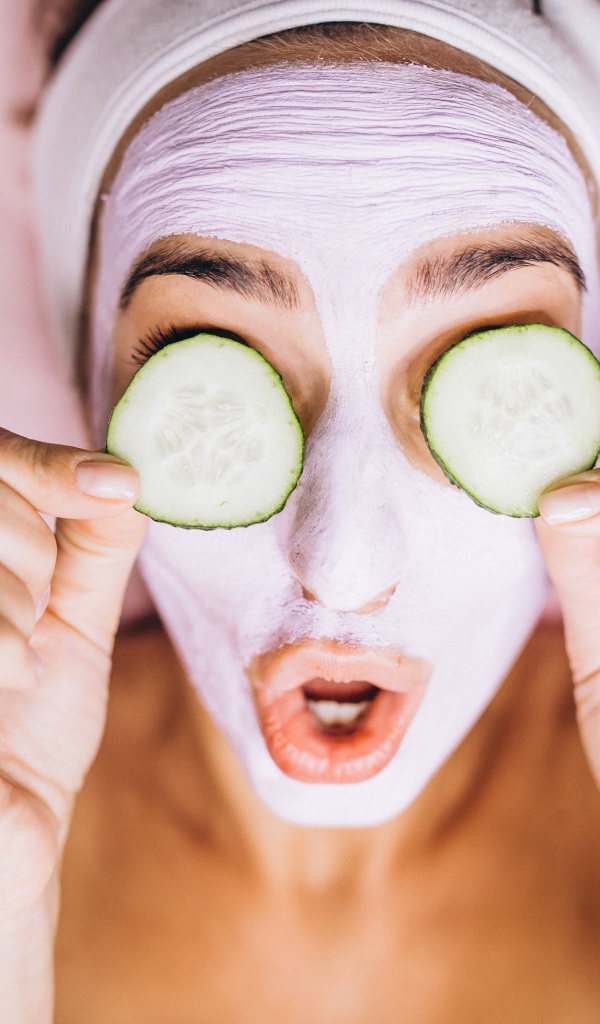 Девушка с маской на лице с огурцами на глазах 