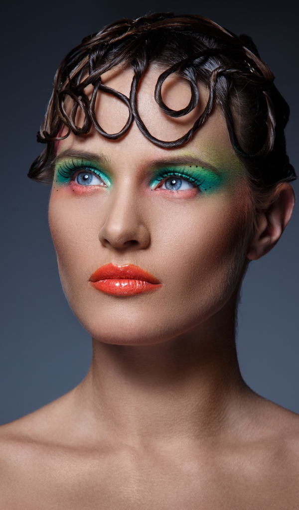 Девушка с ярким макияжем на сером фоне 