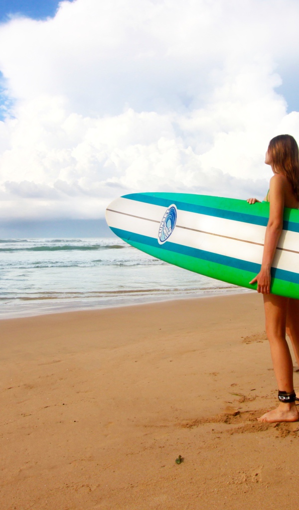 Девушка с доской для серфинга на пляже 