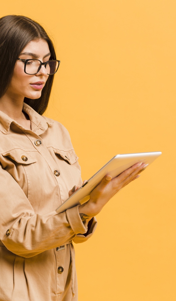 Девушка с планшетов руках на желтом фоне
