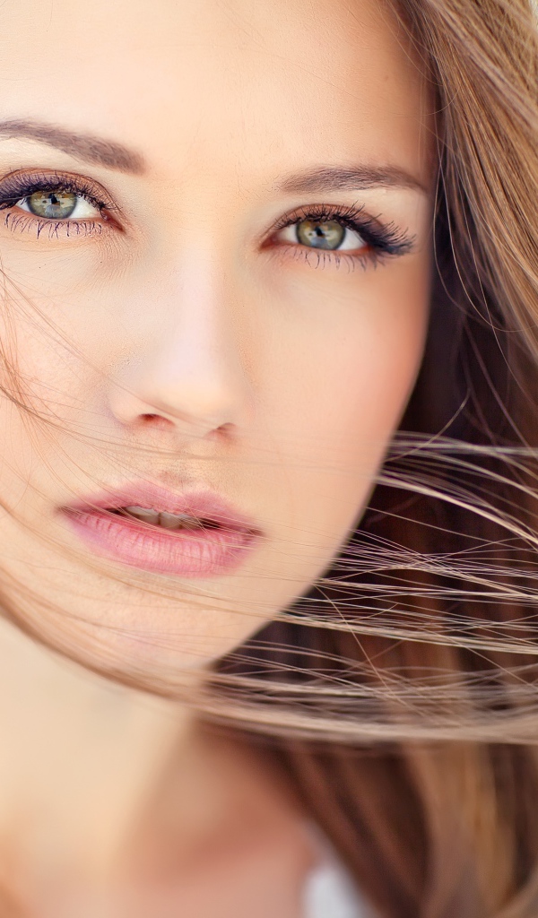 Волосы развеваются ветром на лице у девушки