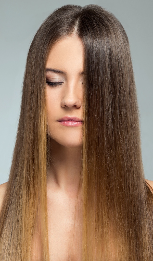 Длинноволосая шатенка с закрытыми глазами на сером фоне 