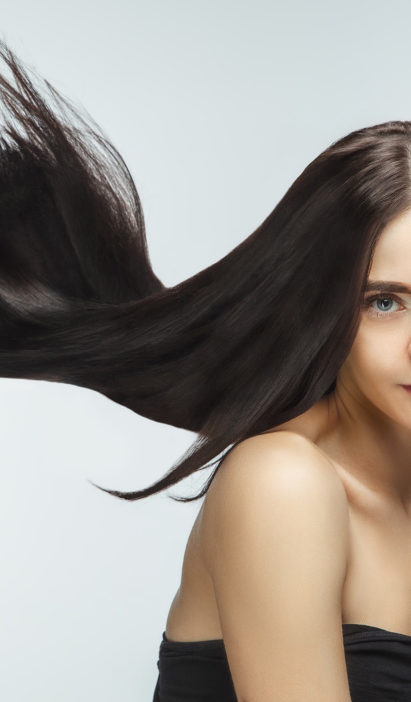 Длинные шелковистые волосы молодой брюнетки 