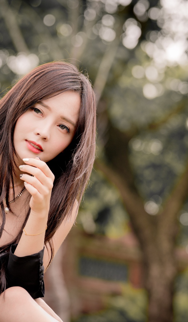 Задумчивая девушка азиатка в черном платье 