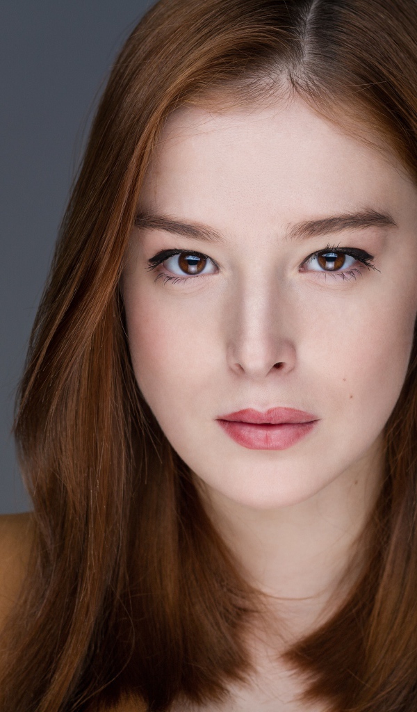 Рыжеволосая  молодая девушка на сером фоне