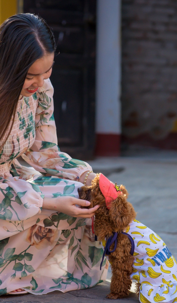 Улыбающаяся девушка азиатка с собакой 