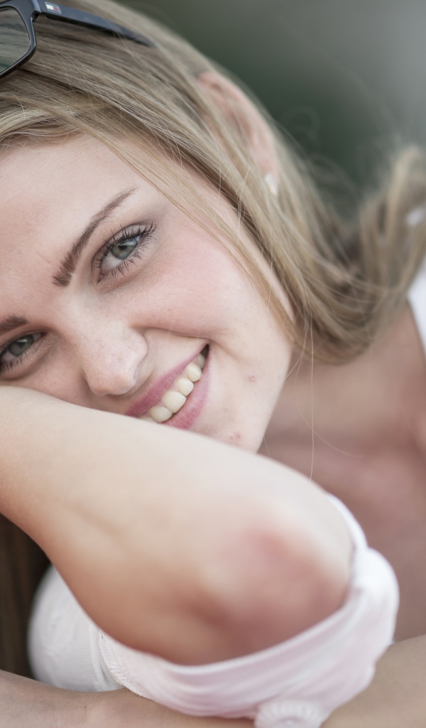 Улыбающаяся девушка блондинка с очками на голове