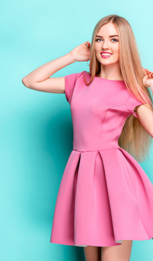 Улыбающаяся блондинка в розовом платье на голубом фоне