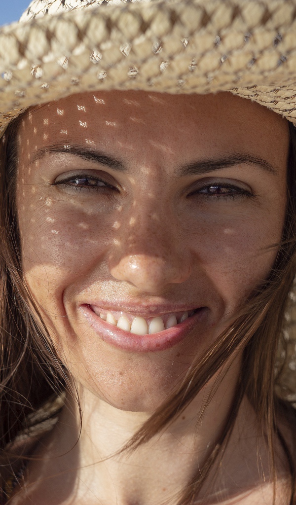 Улыбающаяся кареглазая девушка в соломенной шляпе 