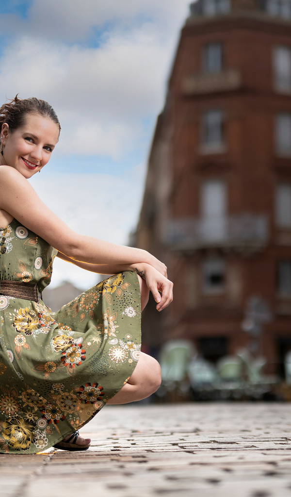 Улыбающаяся девушка в платье на улице города