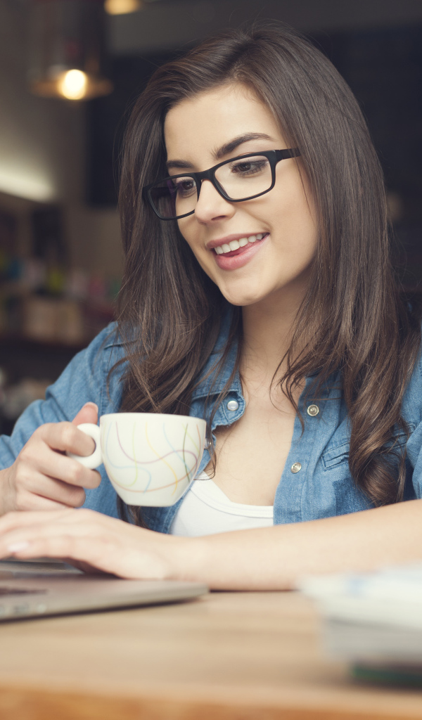 Улыбающаяся девушка в очках с ноутбуком