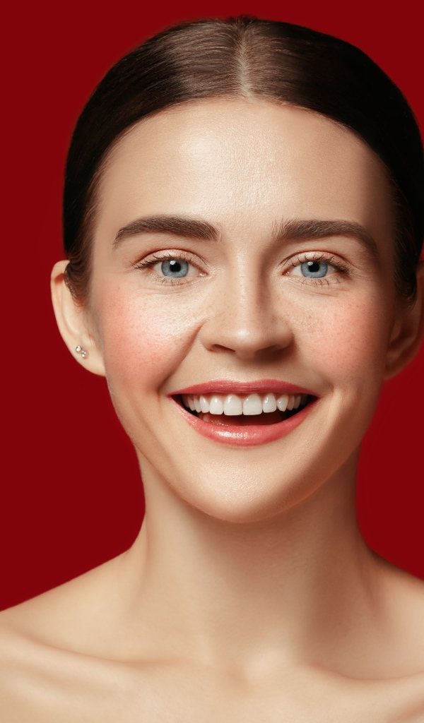 Улыбающаяся молодая девушка на красном фоне