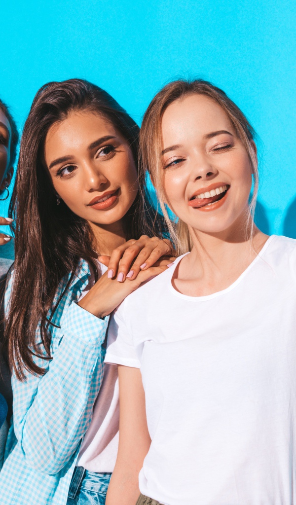 Три подруги делают селфи на голубом фоне