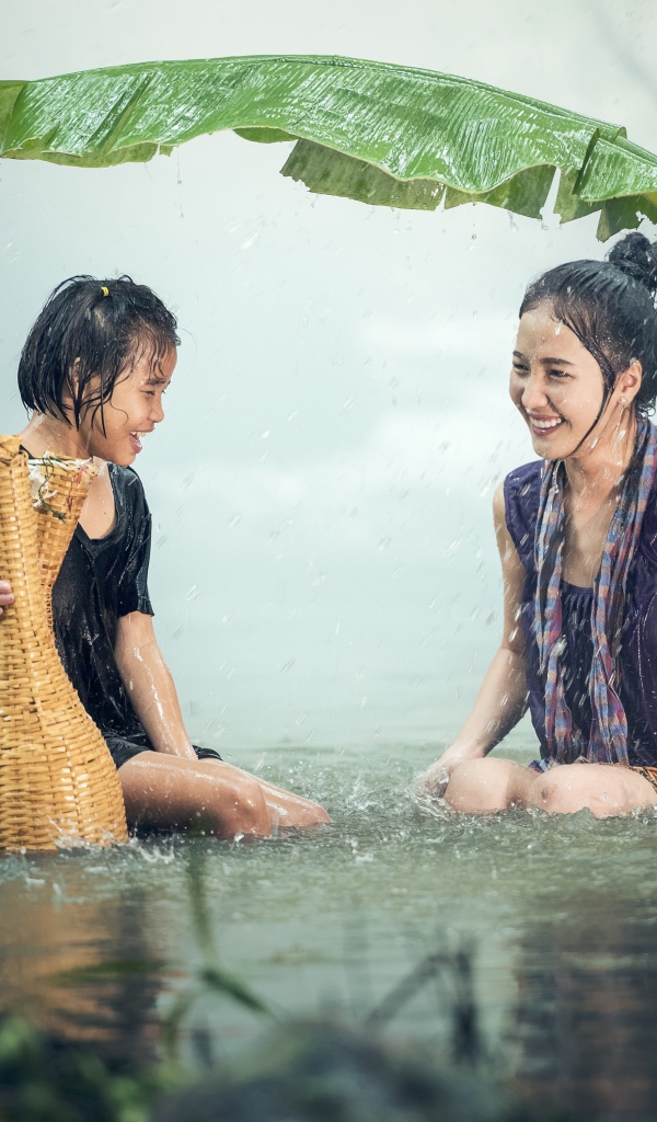 Две девушки азиатки под дождем в воде