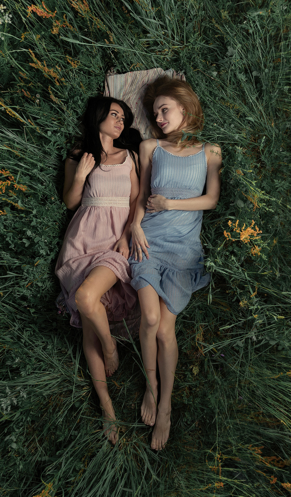 Две девушки лежат в высокой траве