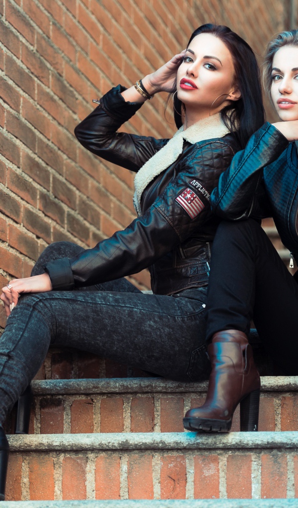 Две красивые девушки сидят на ступенях 