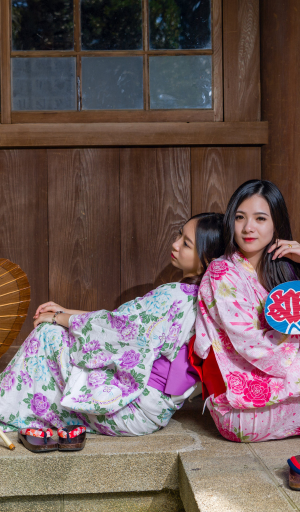 Две молодые девушки в кимоно сидят на полу