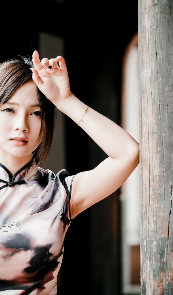 Молодая девушка азиатка стоит у столба 