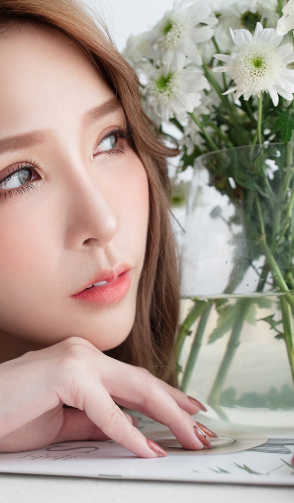 Молодая азиатка с букетом белой хризантемы в вазе